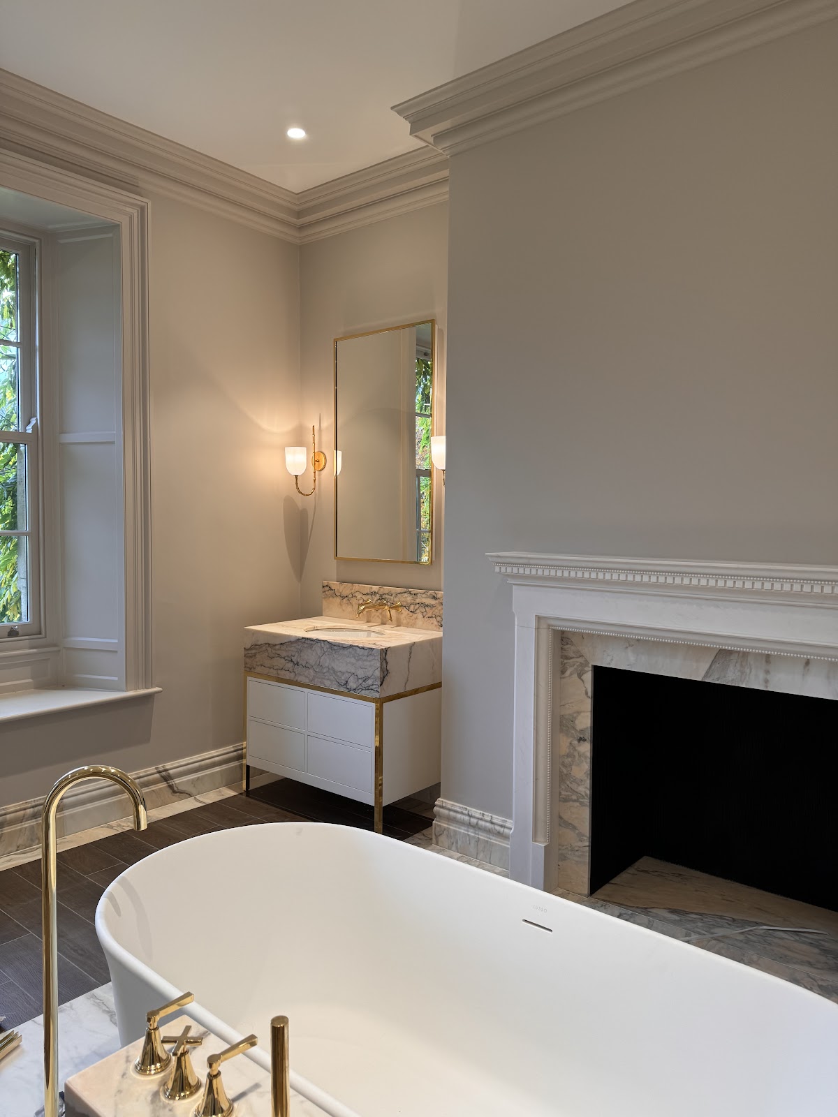 Luxury bathroom with brass wall sconces and recessed downlights