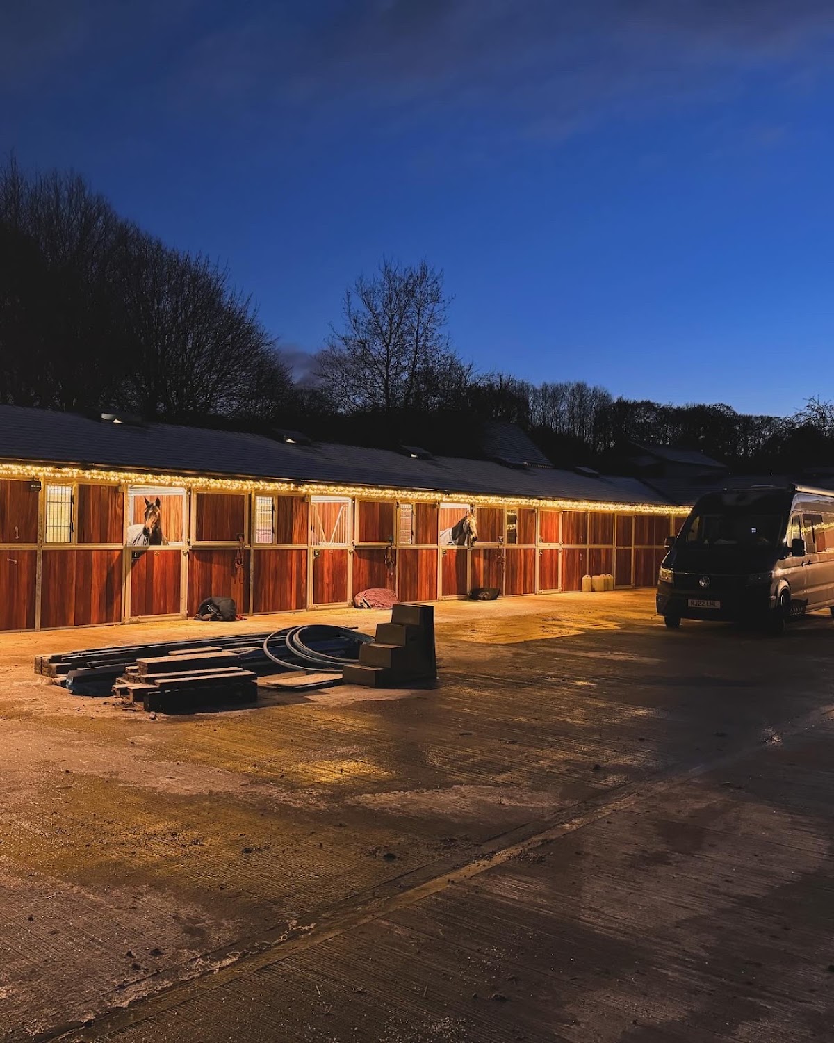 Equestrian yard lit with warm festoon lighting at dusk